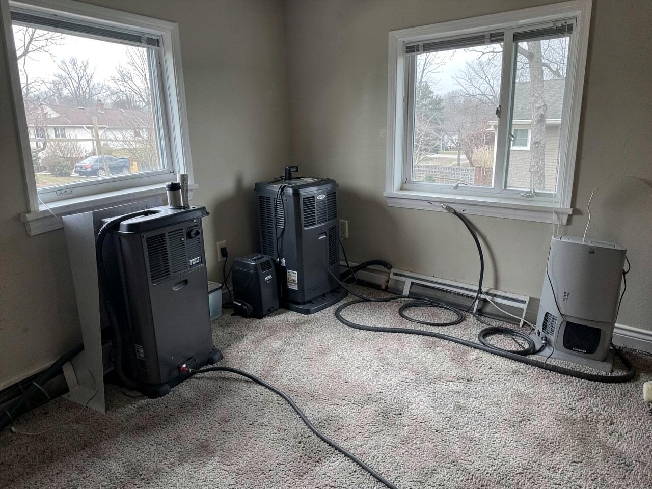 Dehumidifiers and air movers drying a carpeted room in a Mississauga home